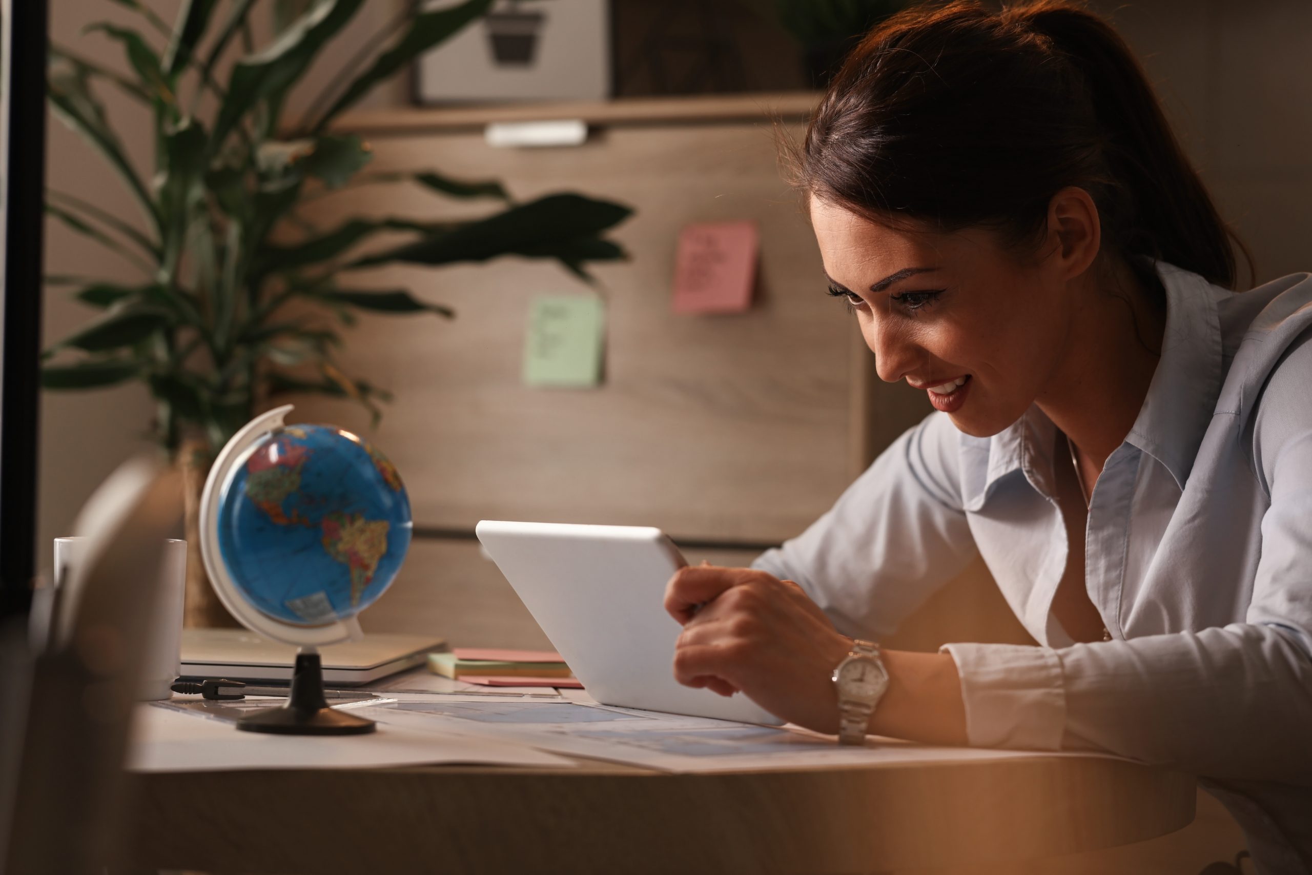 smiling entrepreneur going through business reports digital tablet while working office