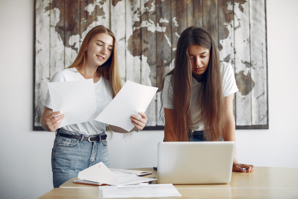 two girls white t shirts working office